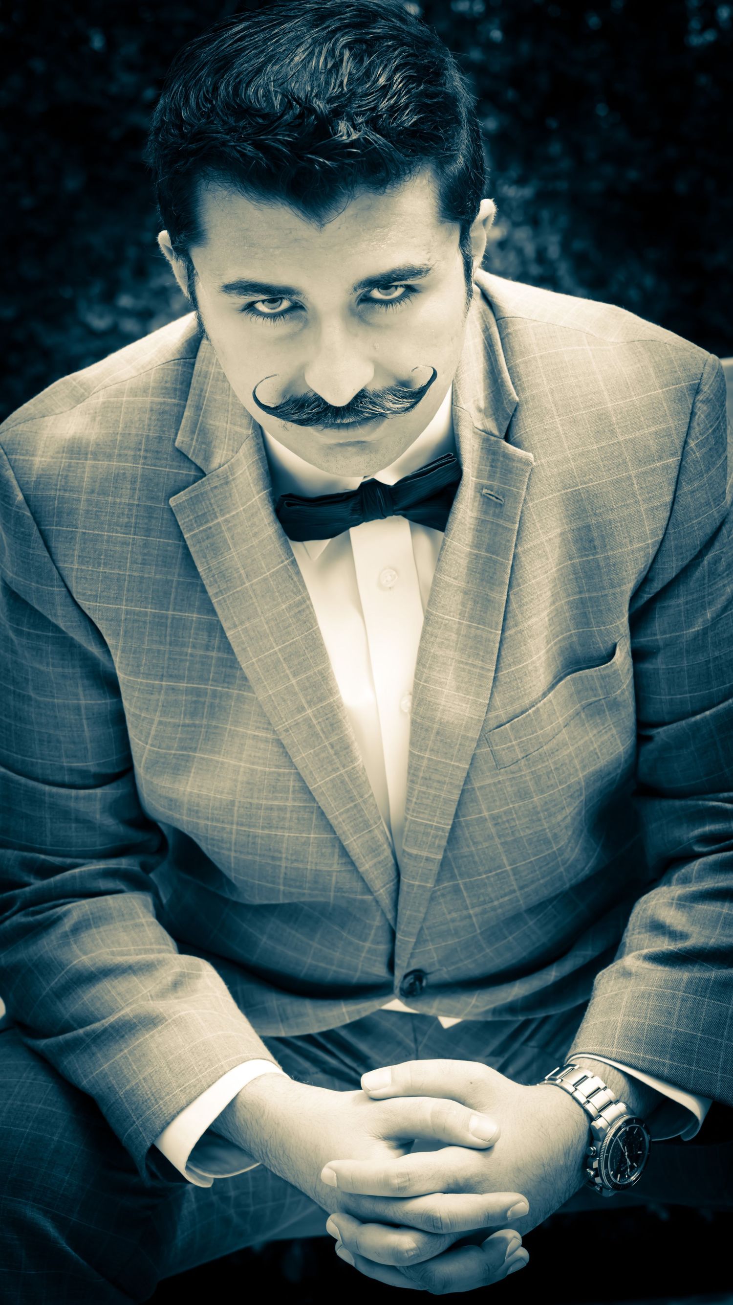 Close-up portrait of person in grey suit checking phone with vintage filter effect.