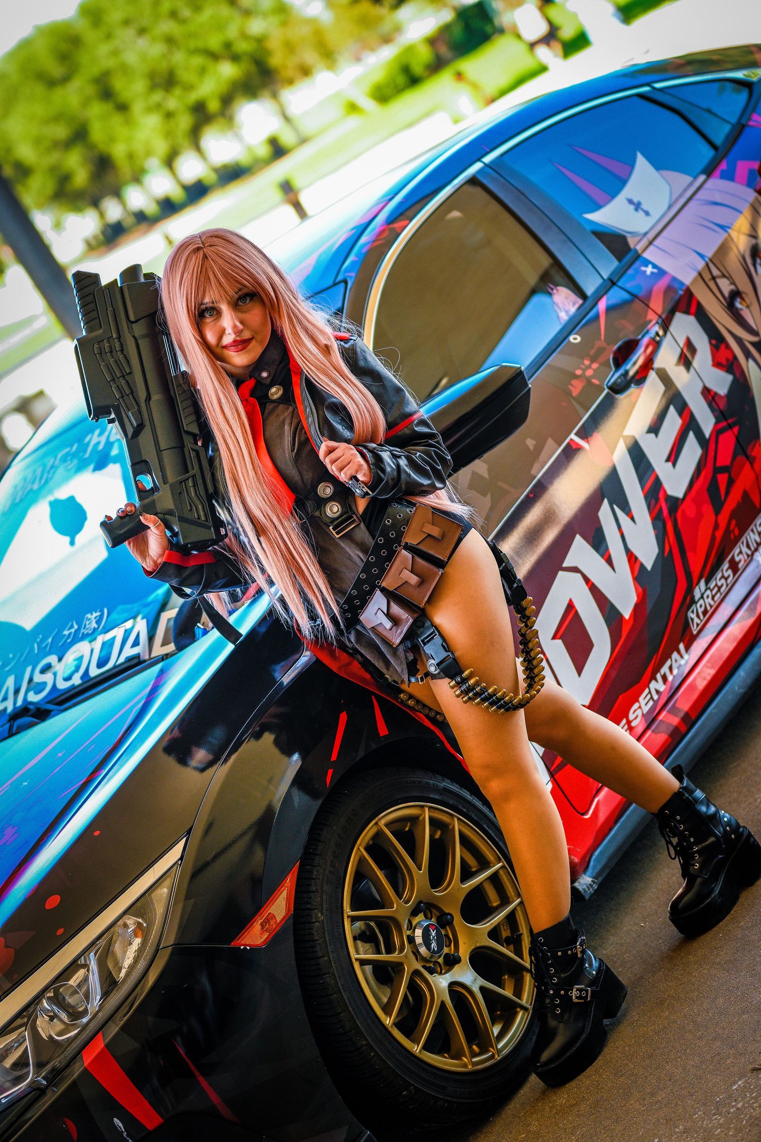 Action-themed cosplay photoshoot featuring a modified sports car with gold wheels.