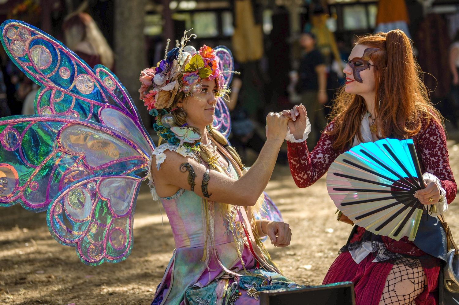 People playing with iridescent bubble wands in an outdoor setting.