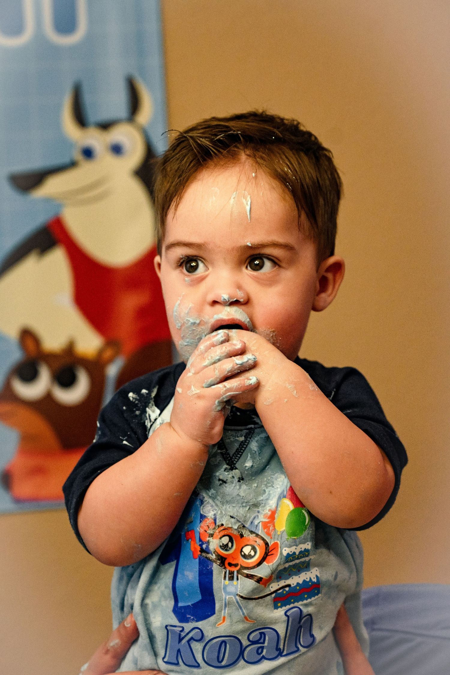 Young child in monster-themed shirt eating at birthday celebration.