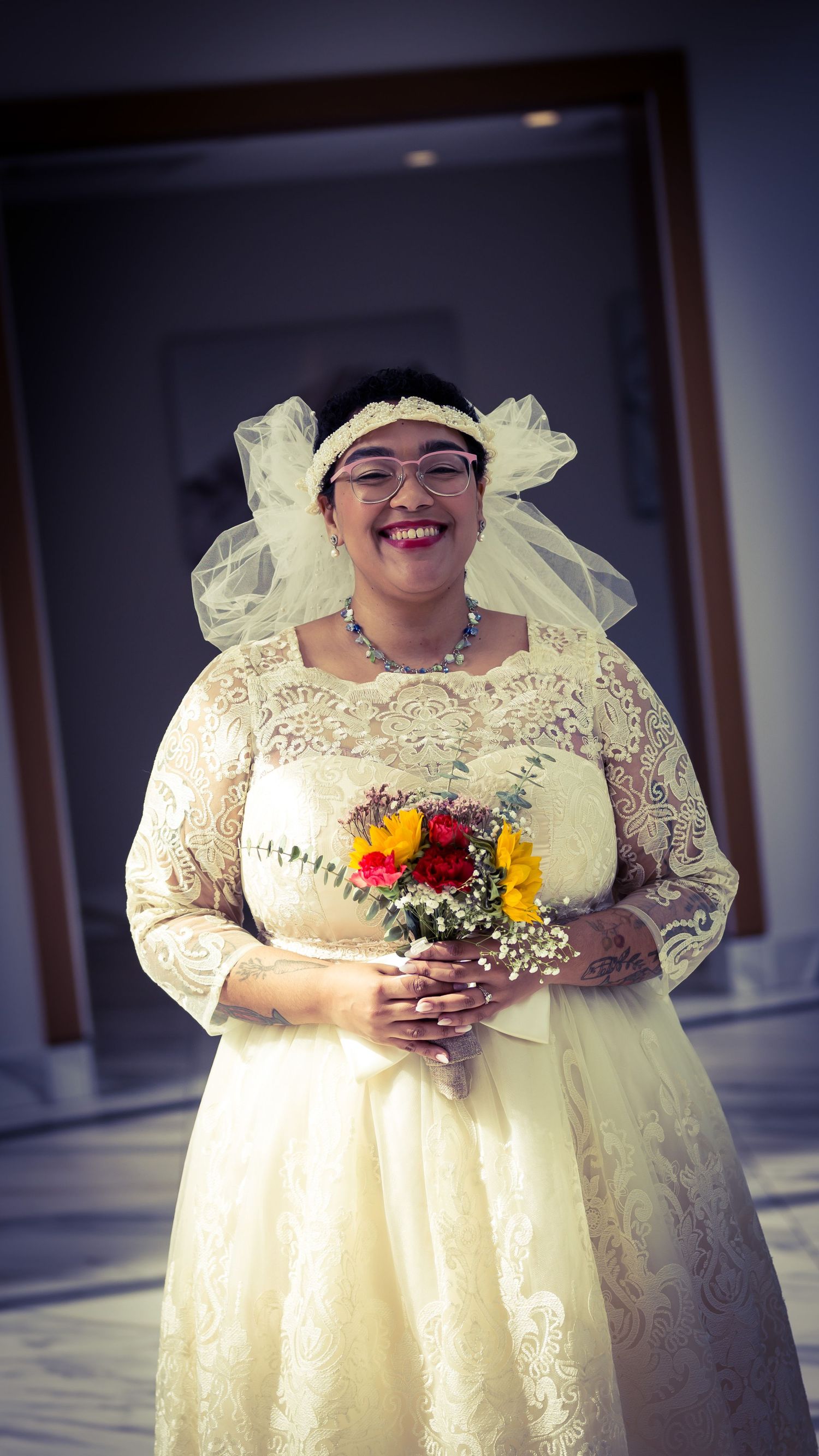 Bride in cream lace dress holds colorful bouquet during wedding photoshoot.