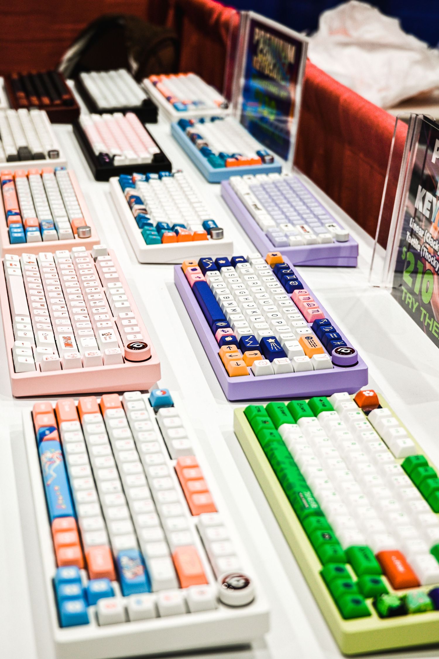 Collection of colorful mechanical keyboards with custom keycaps displayed in a row.
