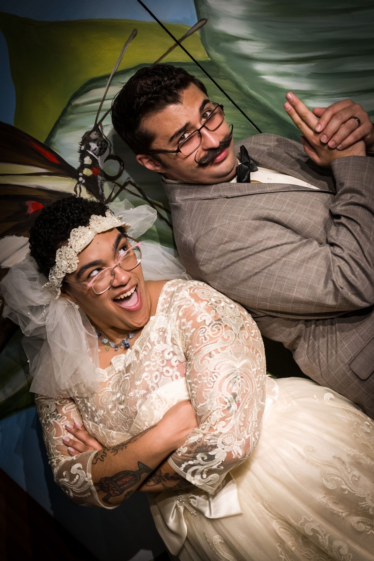A couple shares joyful laughter while lying down in formal wedding attire.