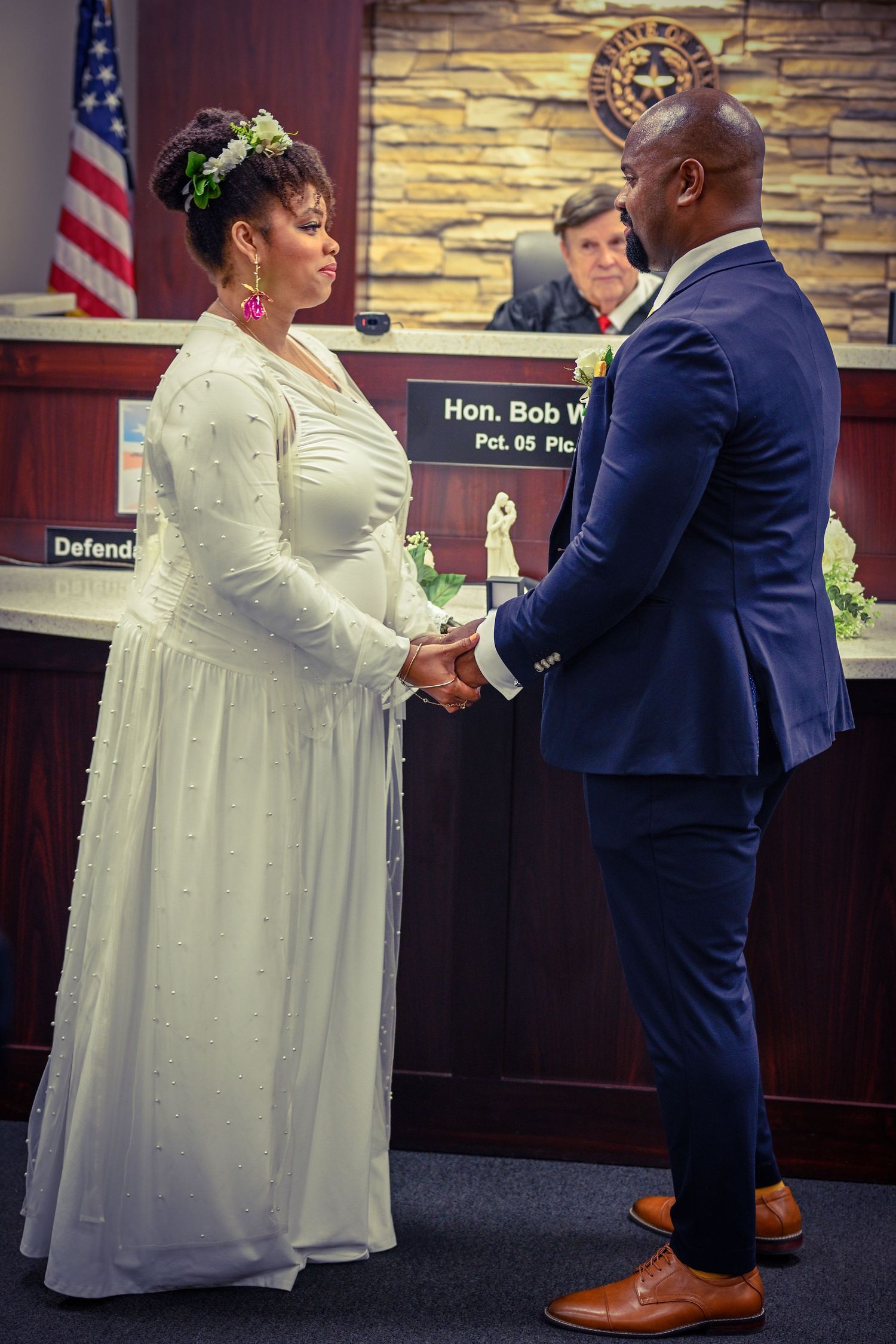 Couple exchanging vows in formal attire at courthouse wedding ceremony.
