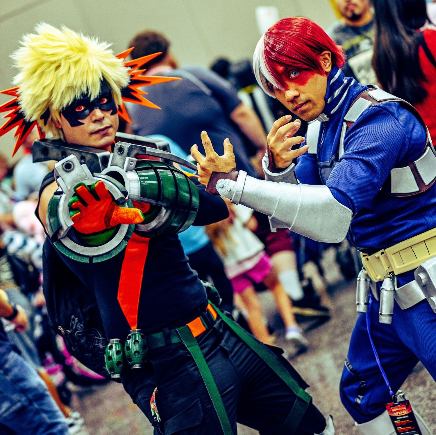 Two cosplayers in dynamic fighting pose wearing anime-inspired costumes.