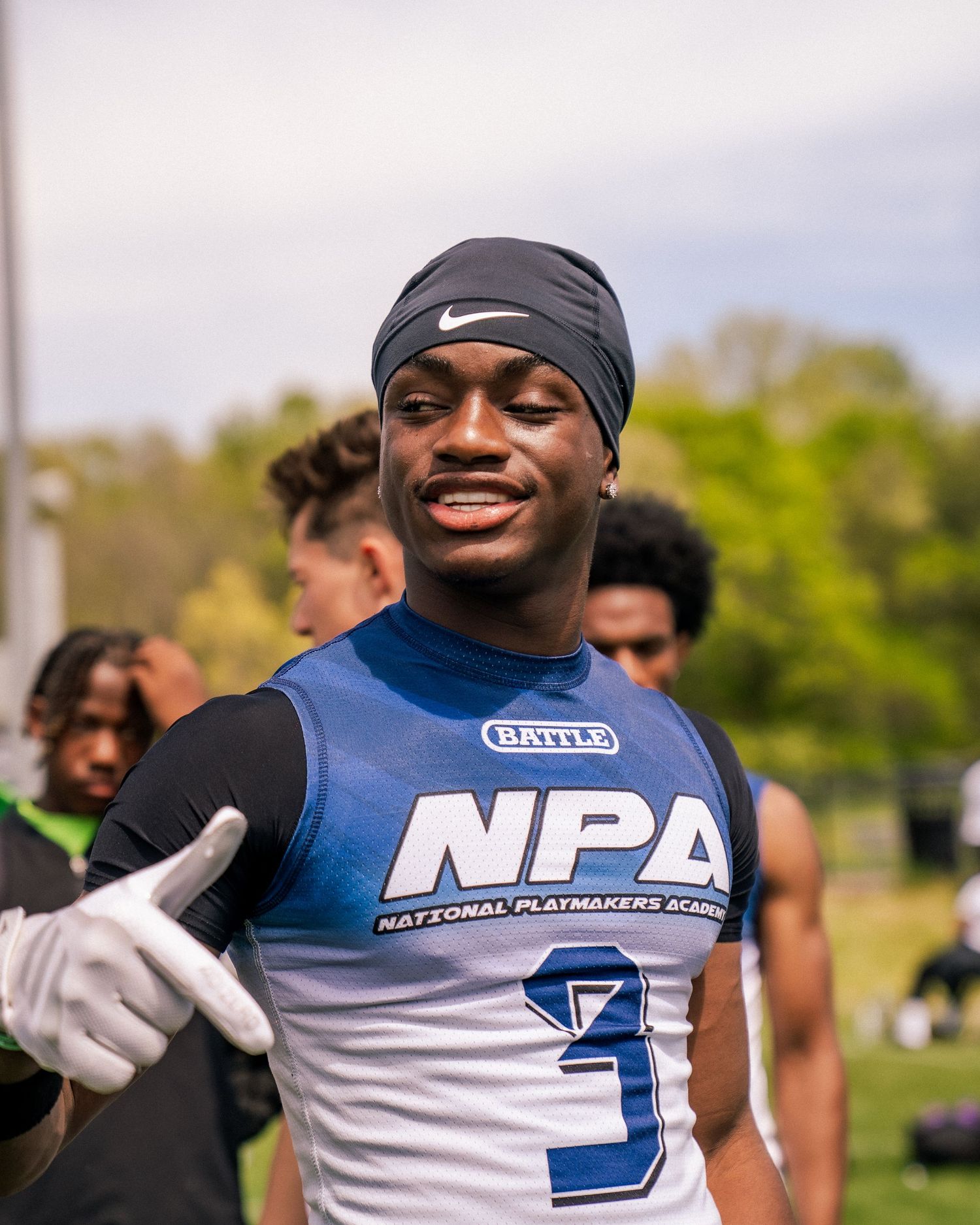 Young football player in NPA jersey smiling and giving thumbs up at National Playmakers Academy camp.
