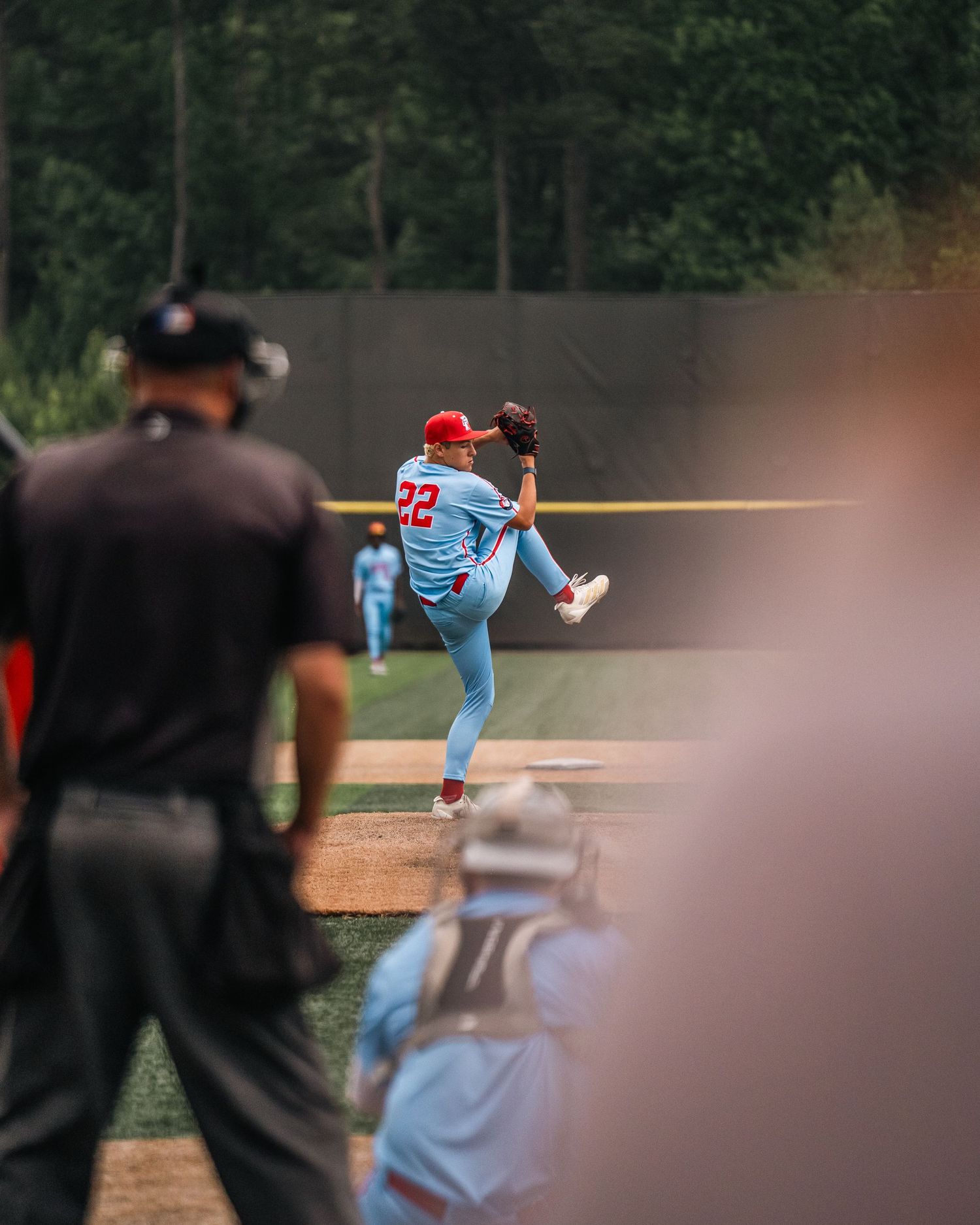 Baseball pitcher #22 in blue uniform mid-windup on mound during game.
