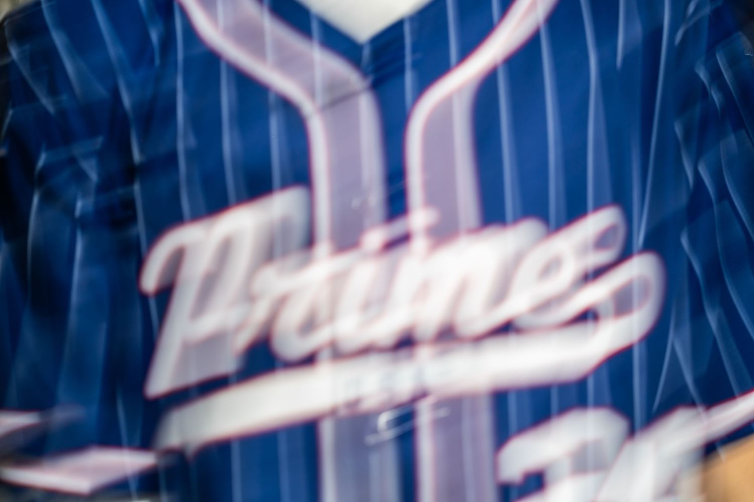 Close-up of a blue pinstripe baseball jersey with cursive Prime logo lettering.