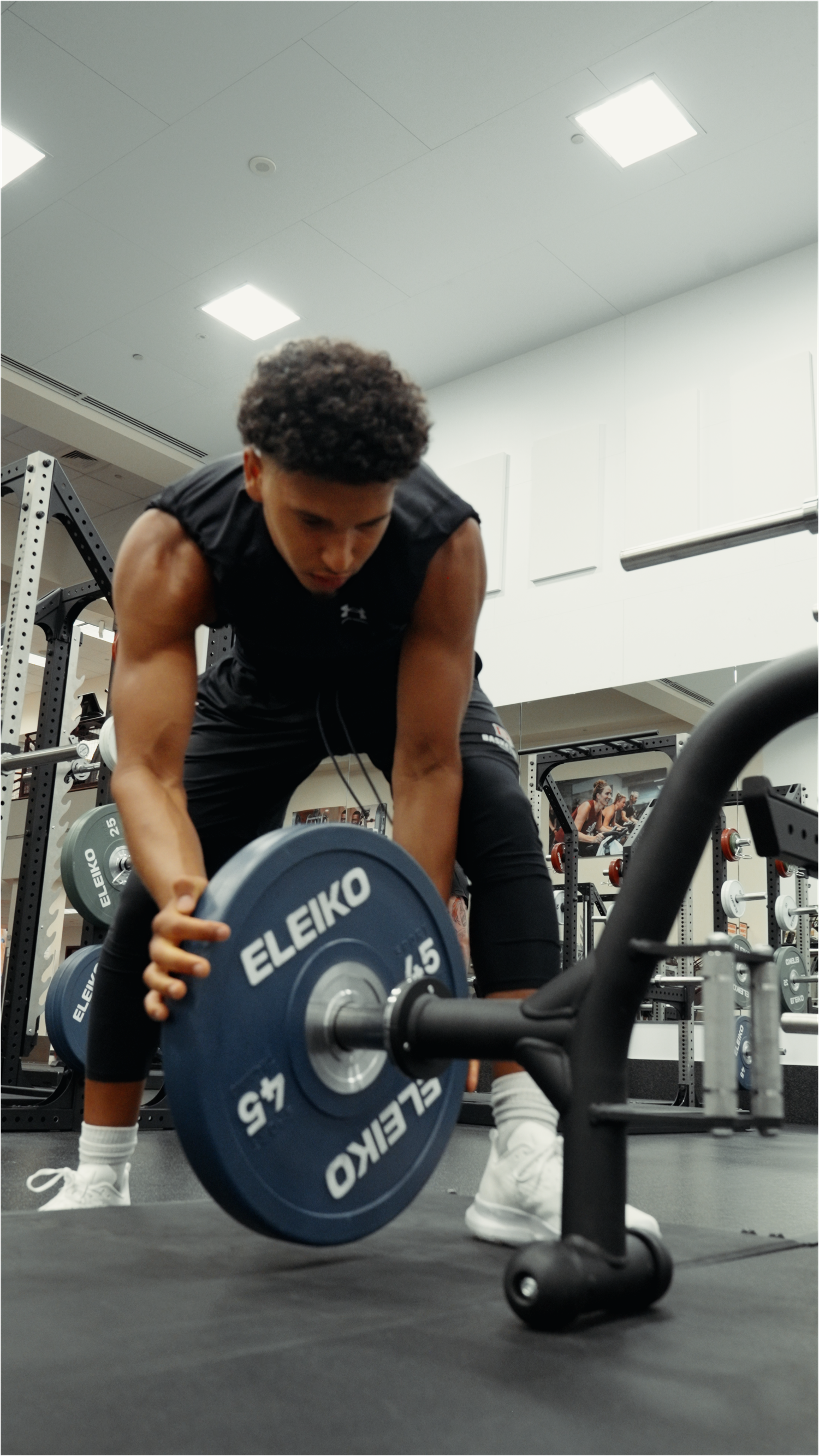 Sequence showing a person performing a rolling dumbbell tricep extension exercise in a modern gym facility.