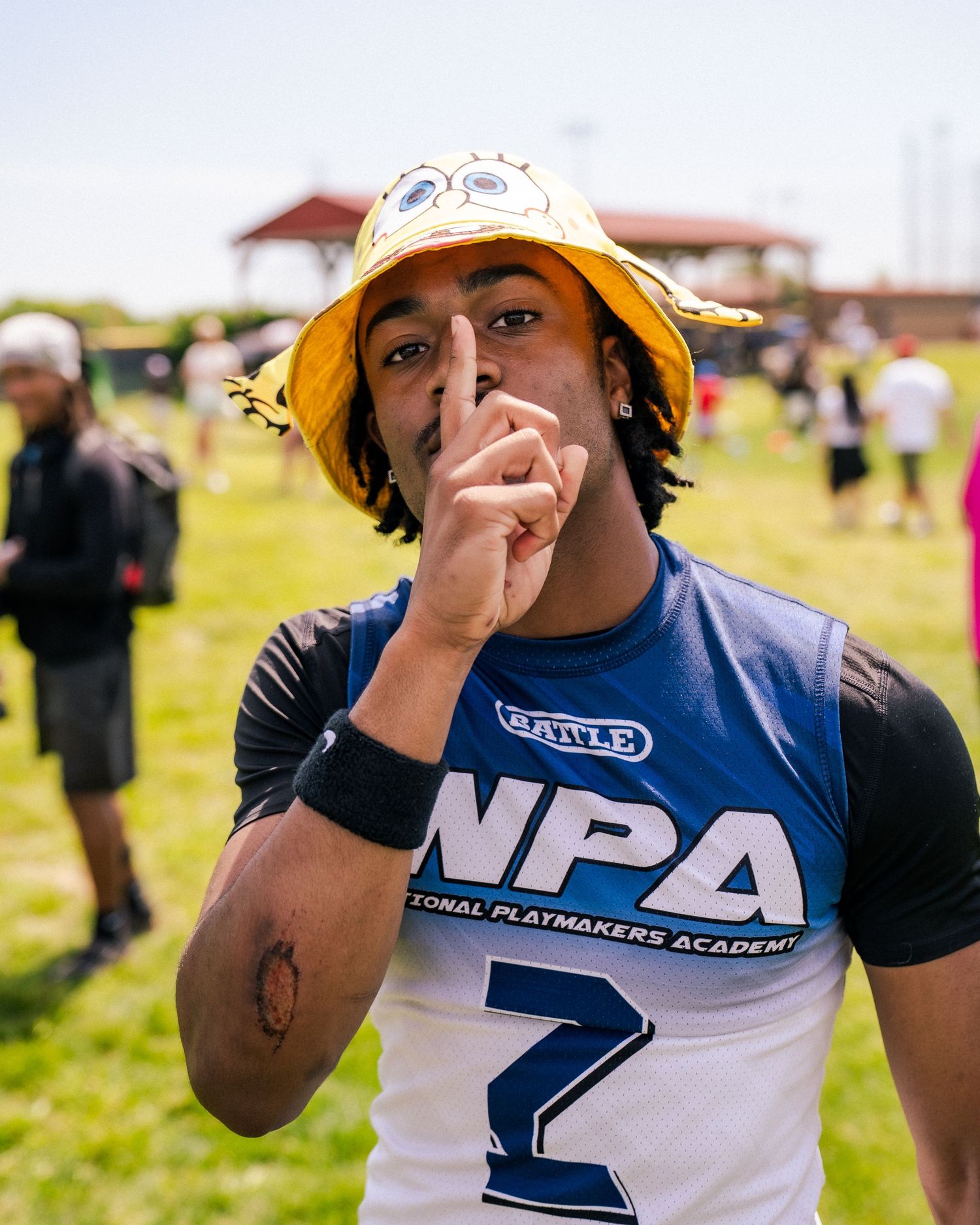 Young athlete in NPA jersey and yellow bucket hat poses confidently at outdoor football event.