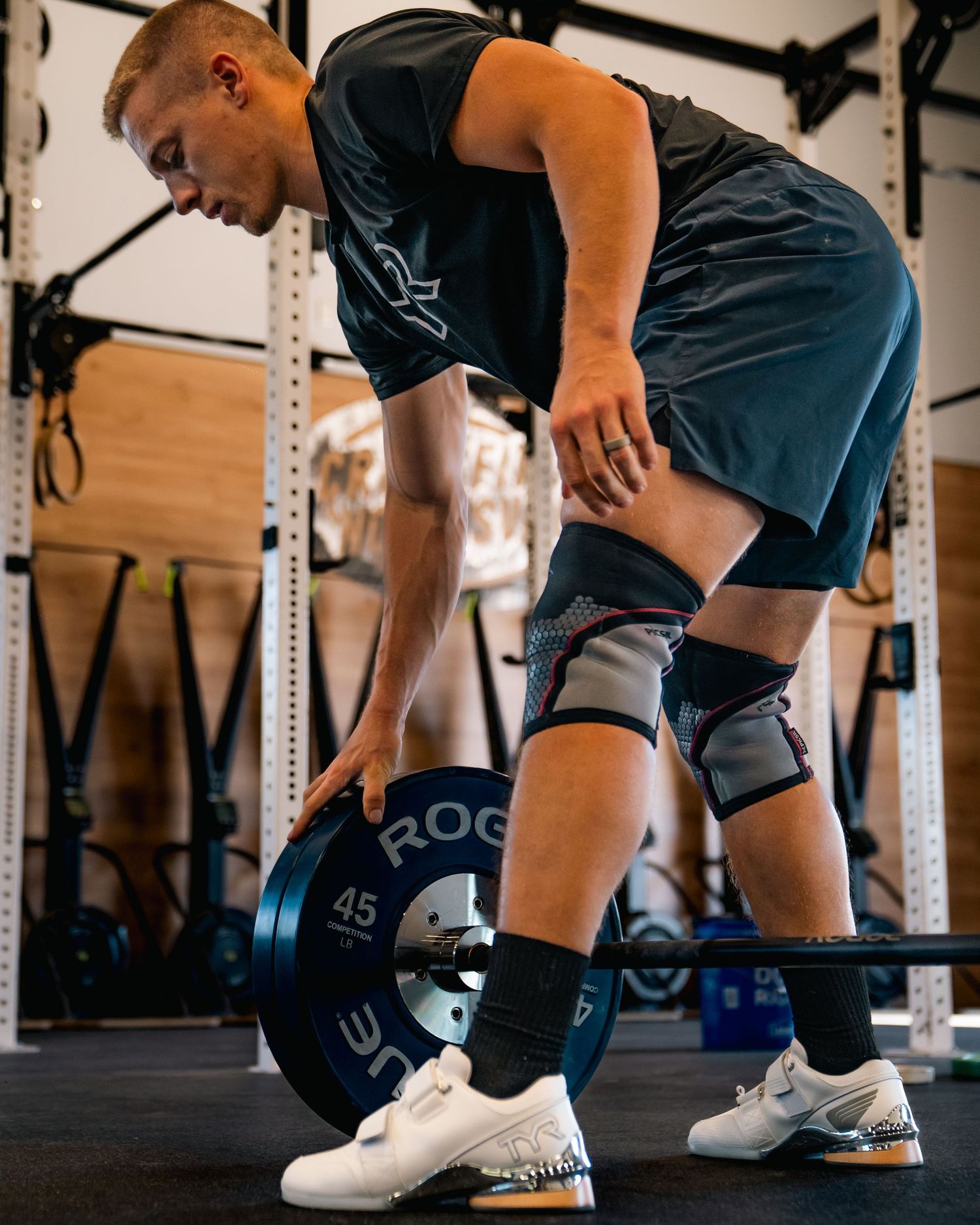 Athlete performing stretching exercises in sequence at a gym with power racks and wooden flooring.