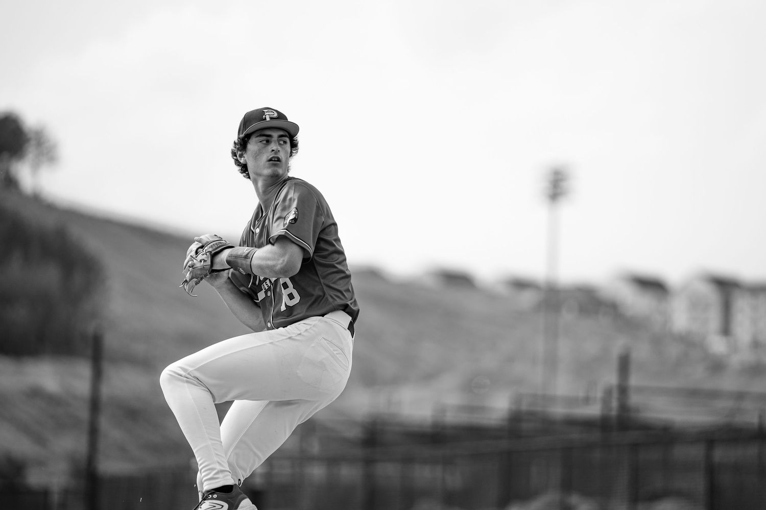 Baseball pitcher in mid-wind-up on mound in black and white action photo.
