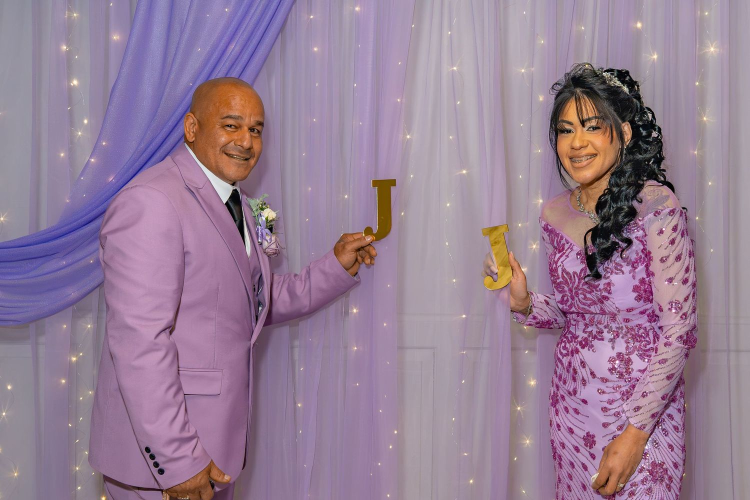 Couple in matching lavender outfits toast champagne glasses at an elegant wedding celebration.