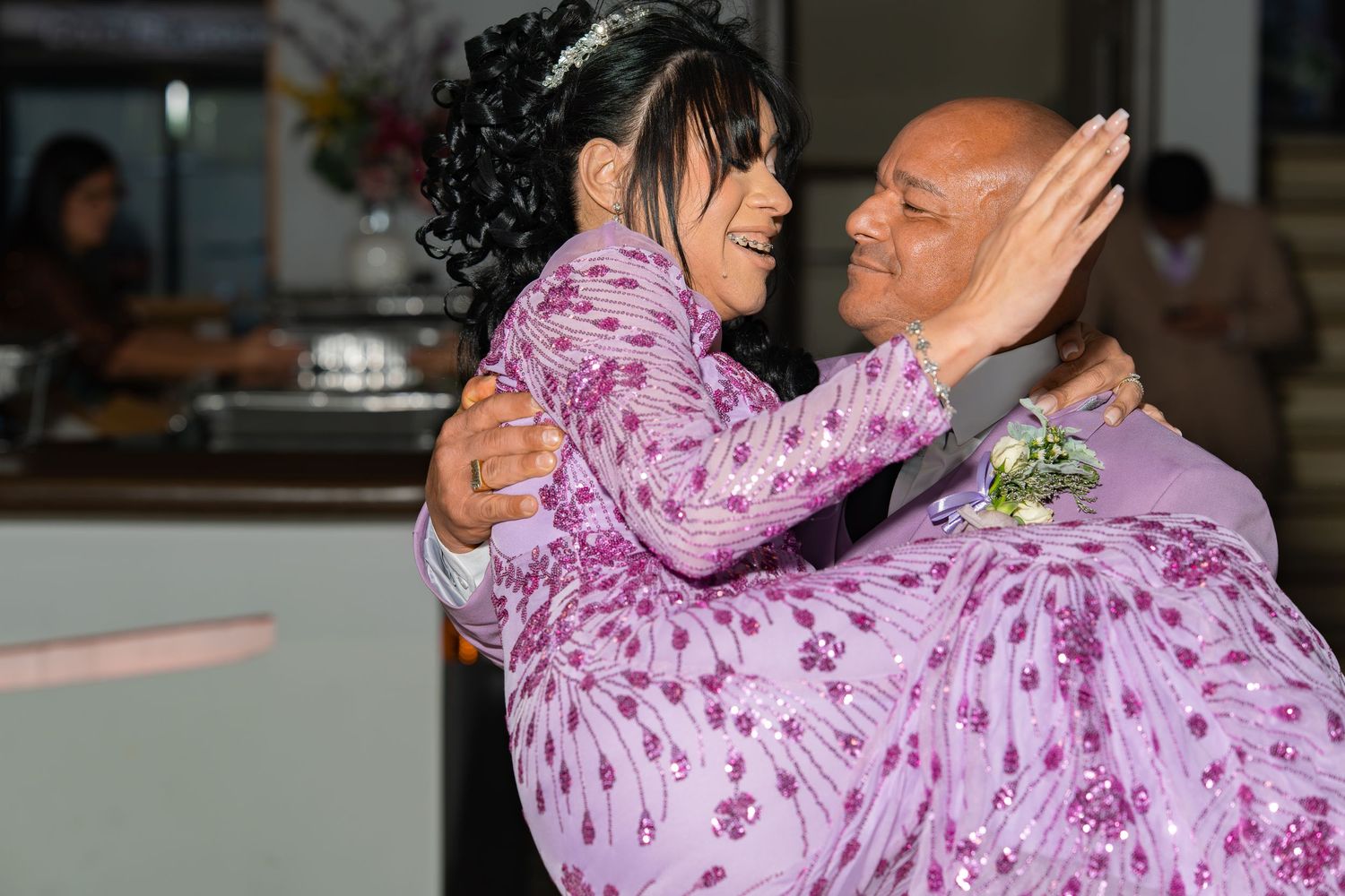 Couple shares a romantic dance embrace at their wedding reception in coordinating lavender outfits.