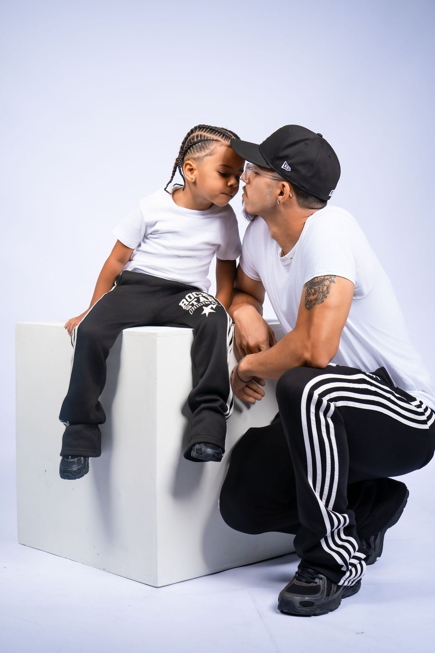 Father kissing his young son on the cheek during a studio photo shoot with white backdrop.