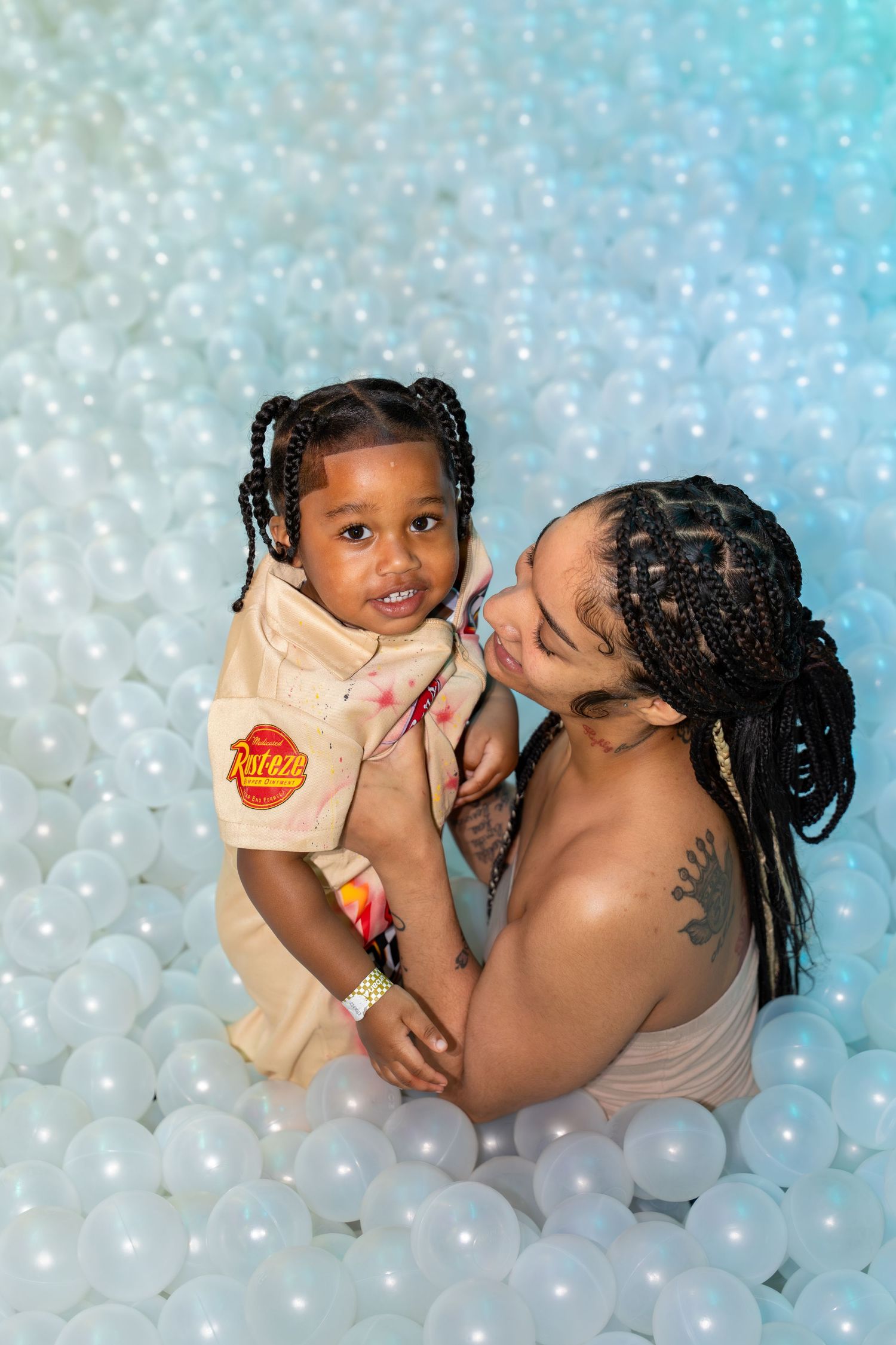 Mother and toddler share a sweet moment together in a white ball pit play area.
