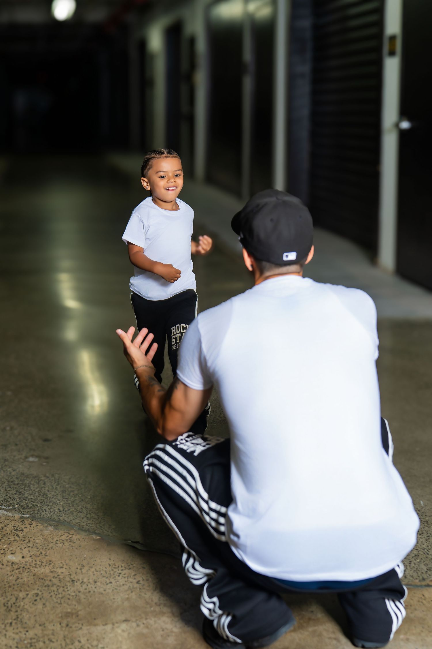 Young boy smiling at his father crouching down in a storage facility hallway.