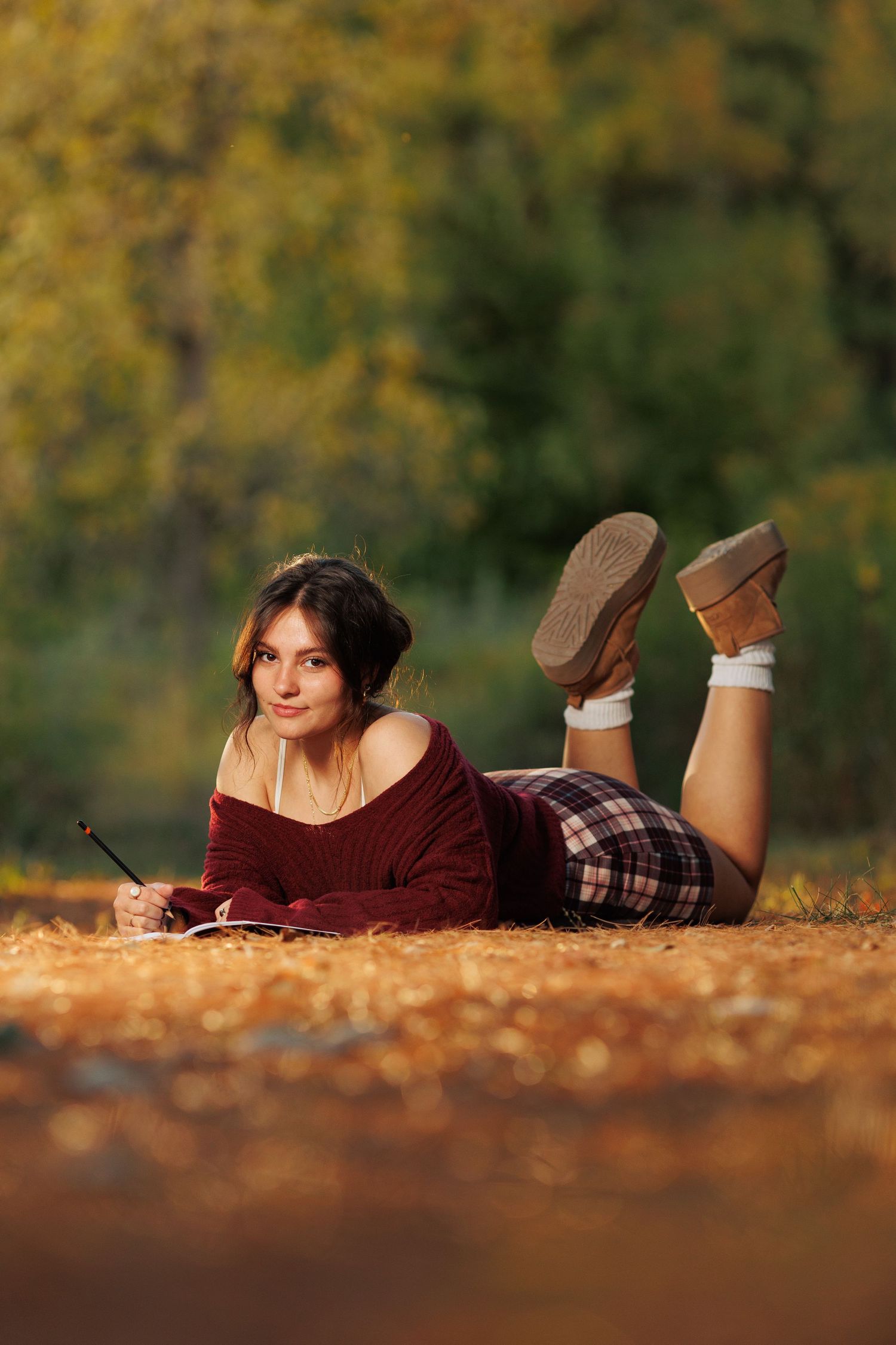 Fall portrait with a pretty high school senior girl posing comfortably on the ground.