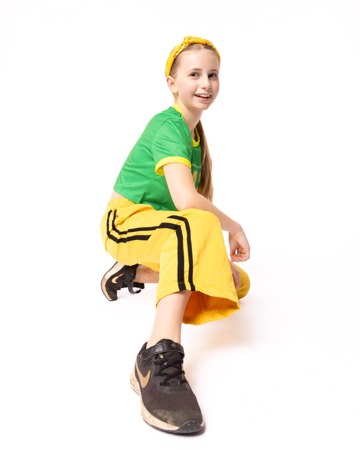 A person in a green shirt and yellow skirt demonstrates a crouching sequence in five progressive poses.