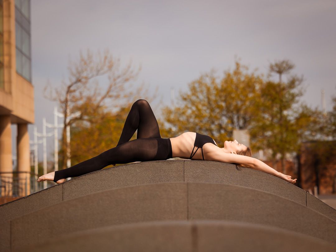 Dancer stretches gracefully on rooftop during outdoor photo session.