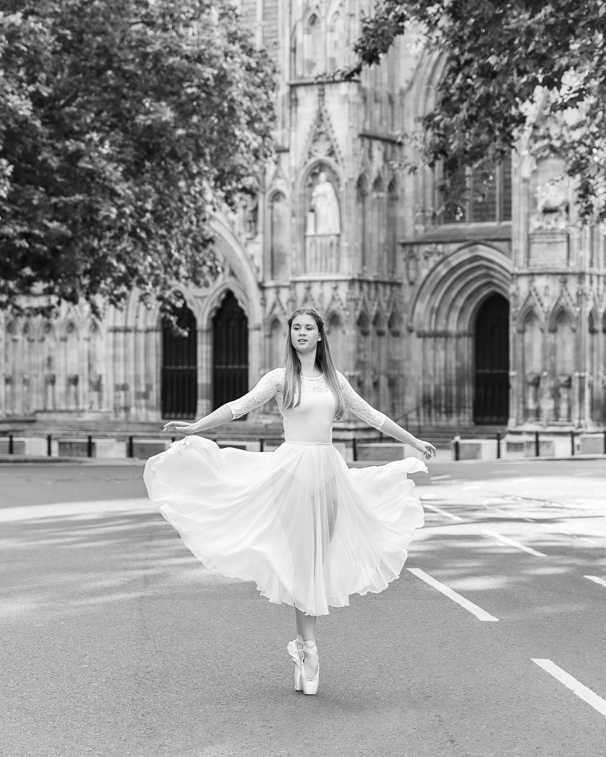 Artistic black and white dance photography series with flowing white dress at cathedral entrance.