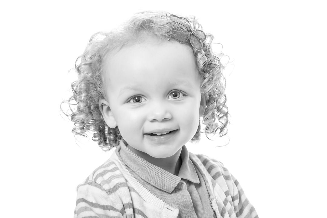 Black and white photo sequence capturing sweet expressions and curly hair in natural lighting.