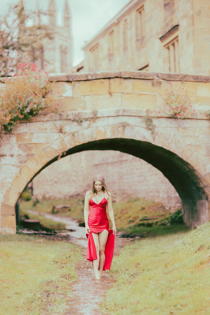 A series of dreamy photos showing a red dress against an old stone bridge in a romantic countryside setting.