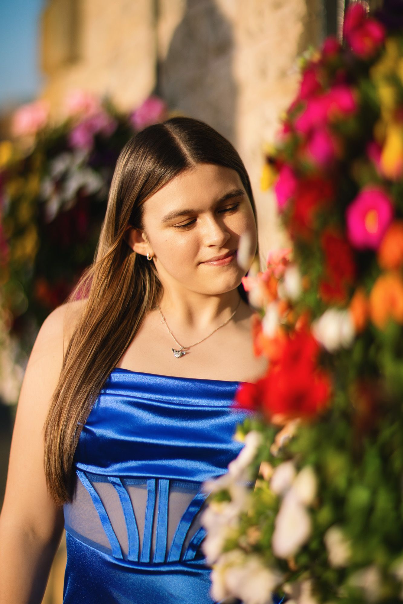 Vibrant blue satin dress photographed against colorful flower garden backdrop.
