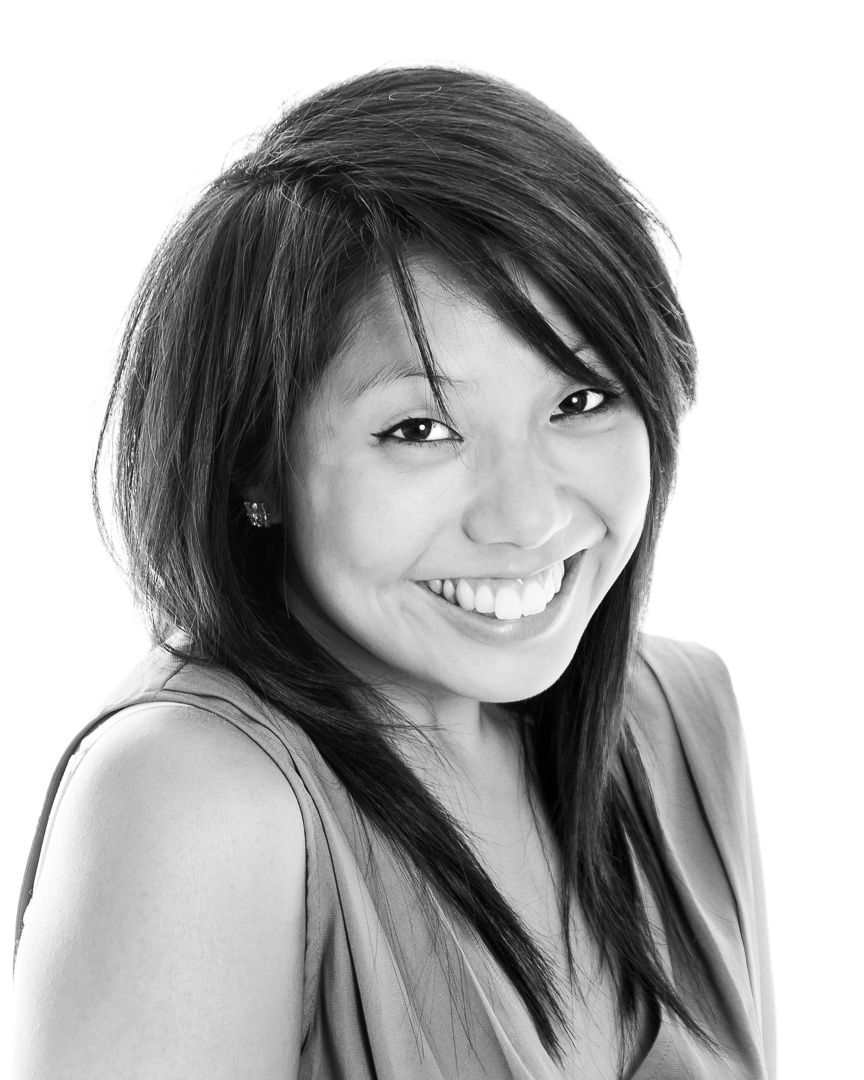 Black and white portrait photograph showing a bright smile and long dark hair against a light background.