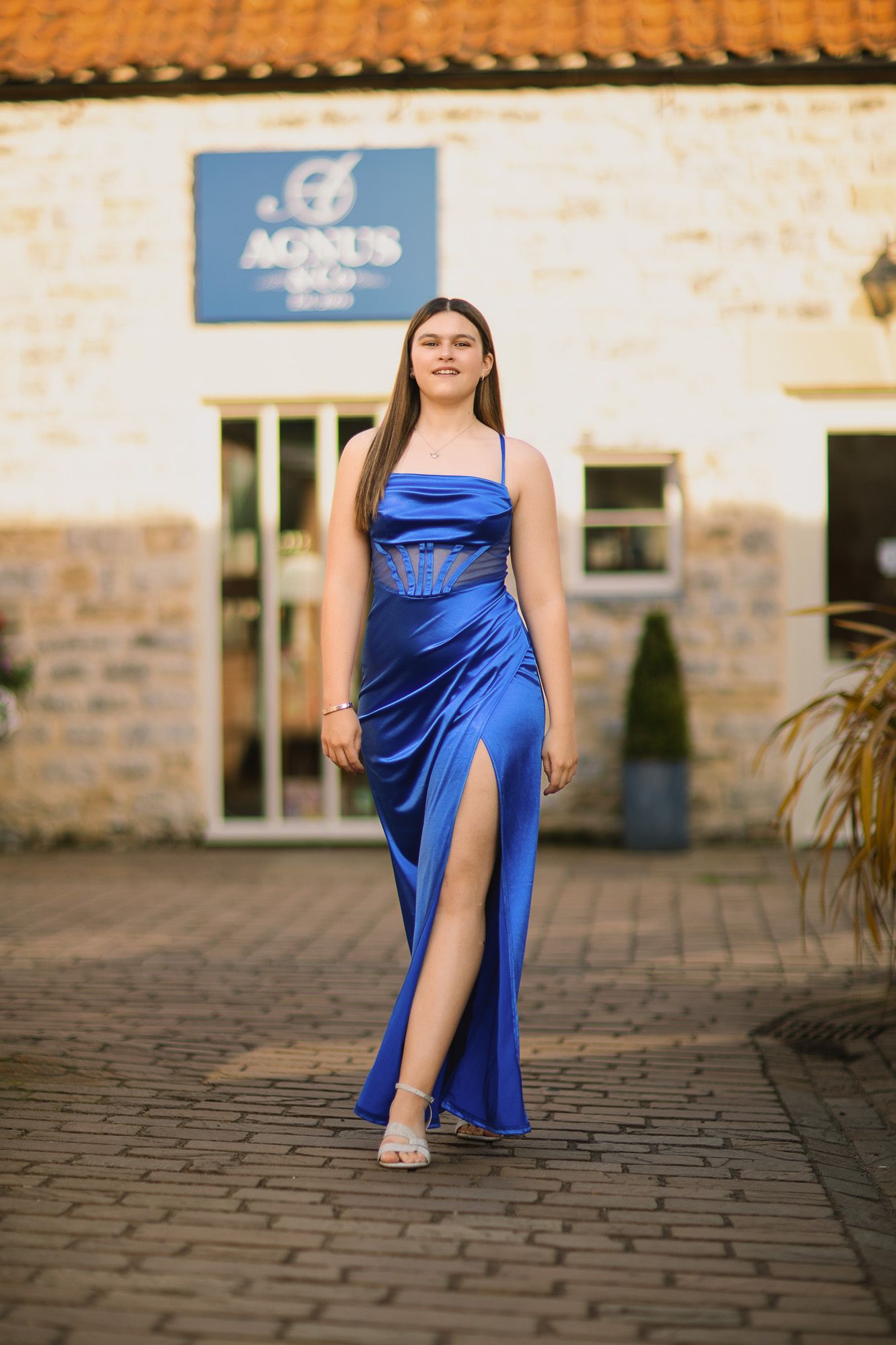 Cobalt blue evening gown captured in outdoor photoshoot on cobblestone path.