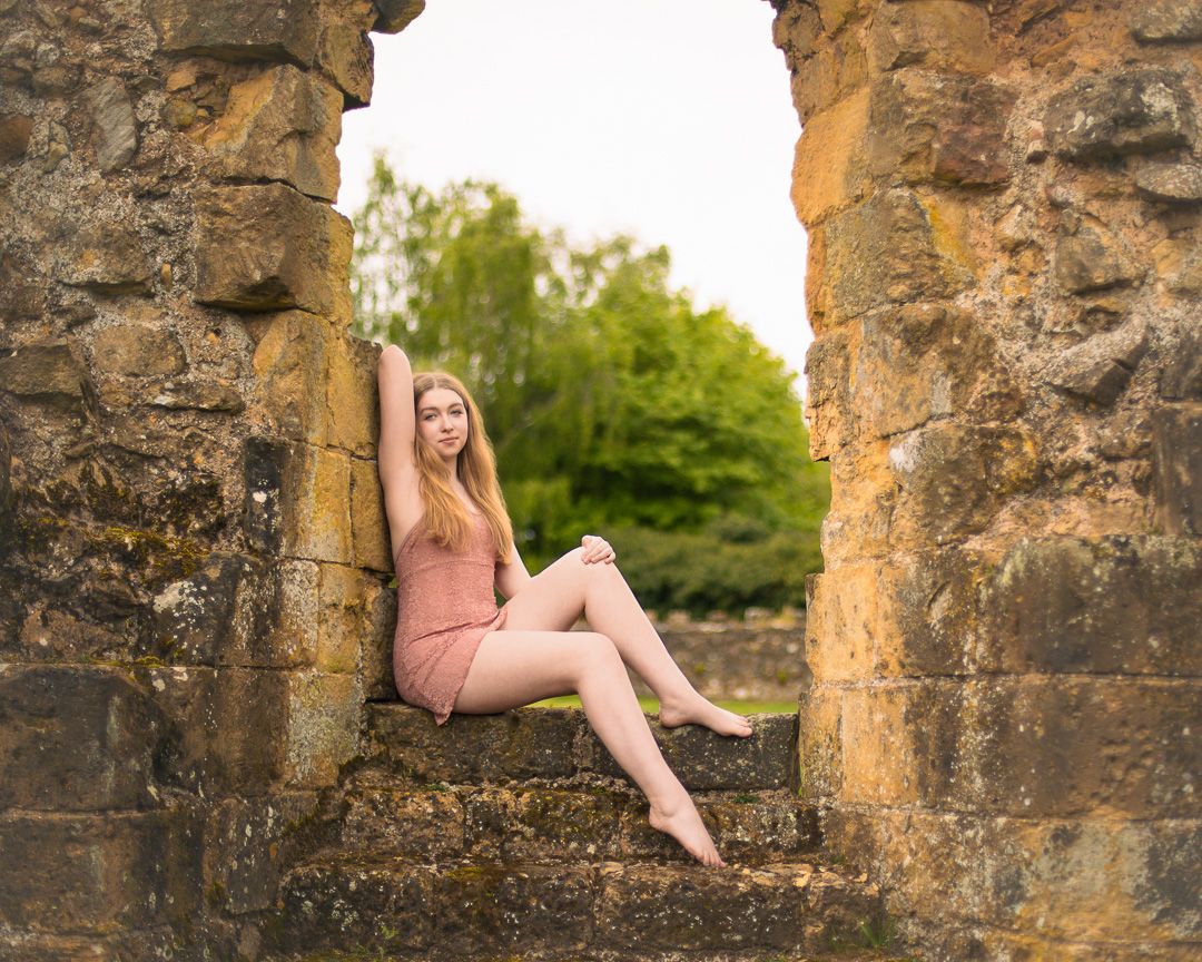 Ballet dancer's legs gracefully posed along ancient stone ruins at sunset.