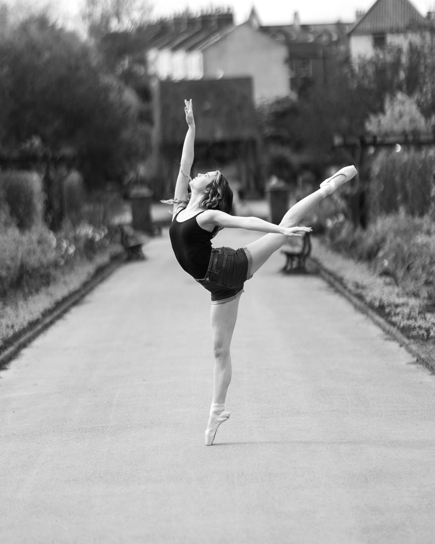 Black and white photo series of ballet dancer performing high kicks on street.