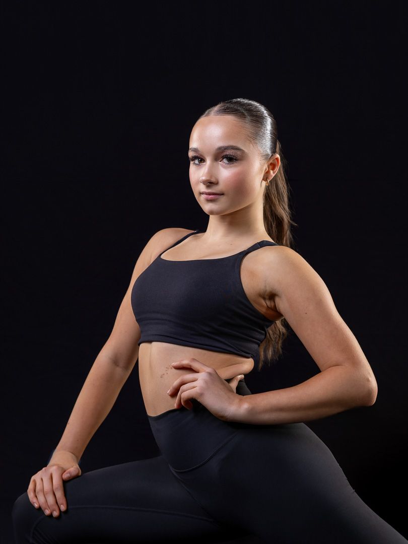 Athletic dancer in black outfit demonstrates powerful dance pose.