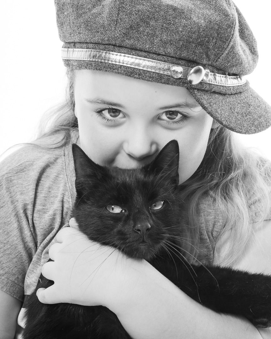 Person in gray clothing cuddling with a black cat in a series of affectionate poses.