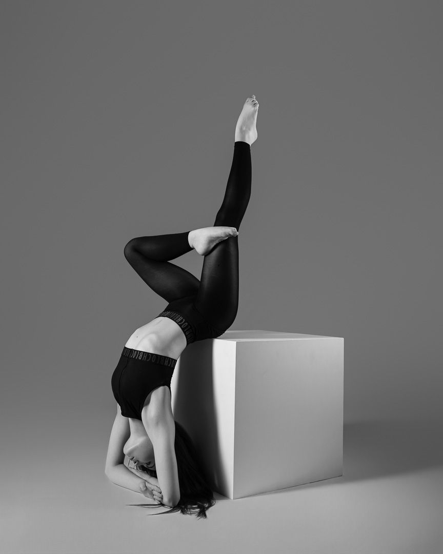 Black and white artistic photo series showing a figure in dark clothing performing dynamic poses against a light background.