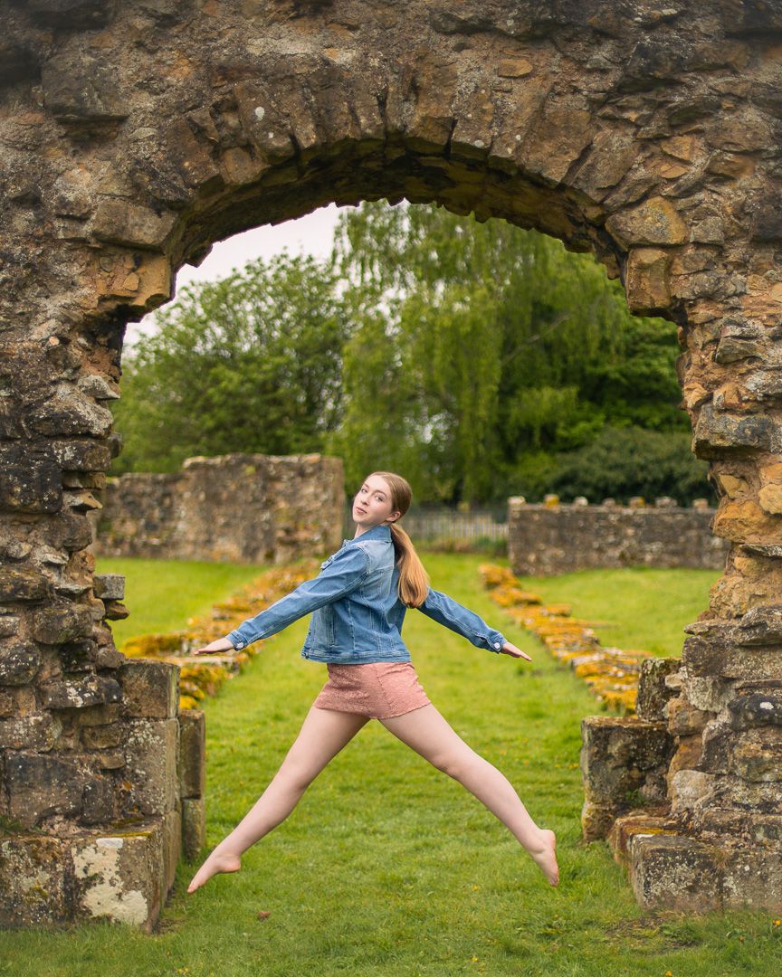 Dancer performs leaps and stretches through stone archways of ancient ruins.
