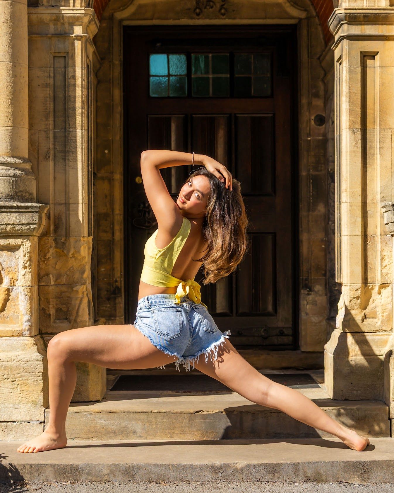 Dancer performs graceful split poses in sequence against historic stone colonnade in warm sunlight.