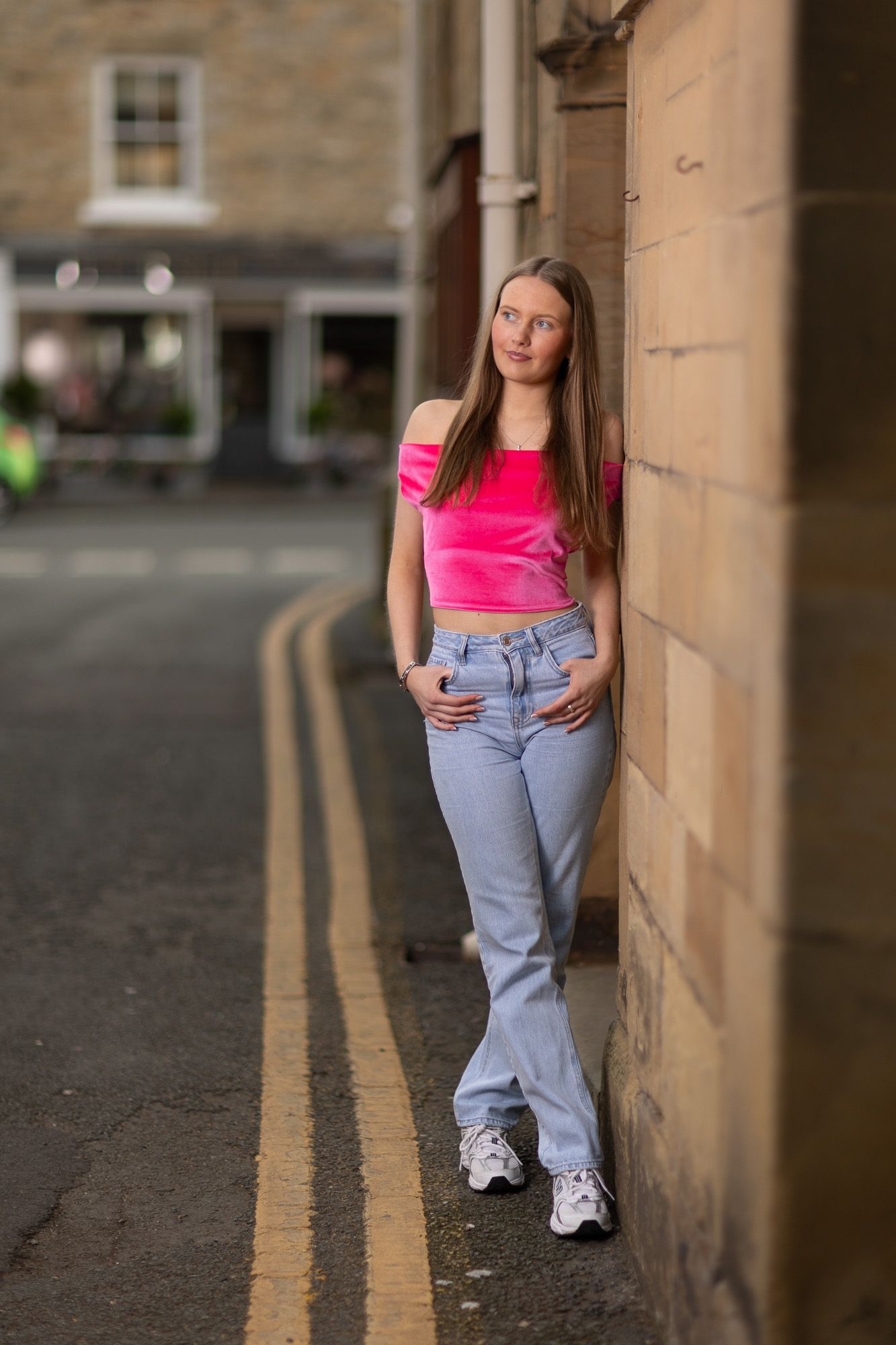 Street style photography with neon pink top and light denim in urban location.