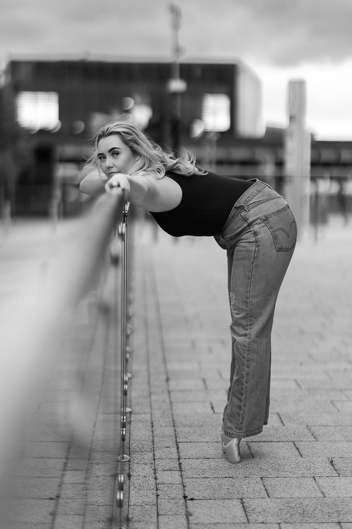 Close-up of ballet shoes and denim on textured pavement in black and white photography.
