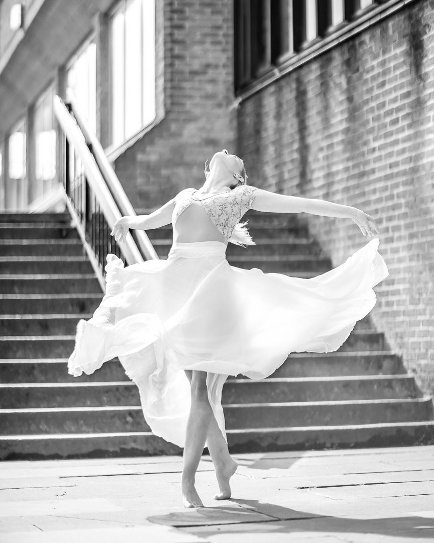 Dancer in flowing white dress creates dynamic movement on stone steps.