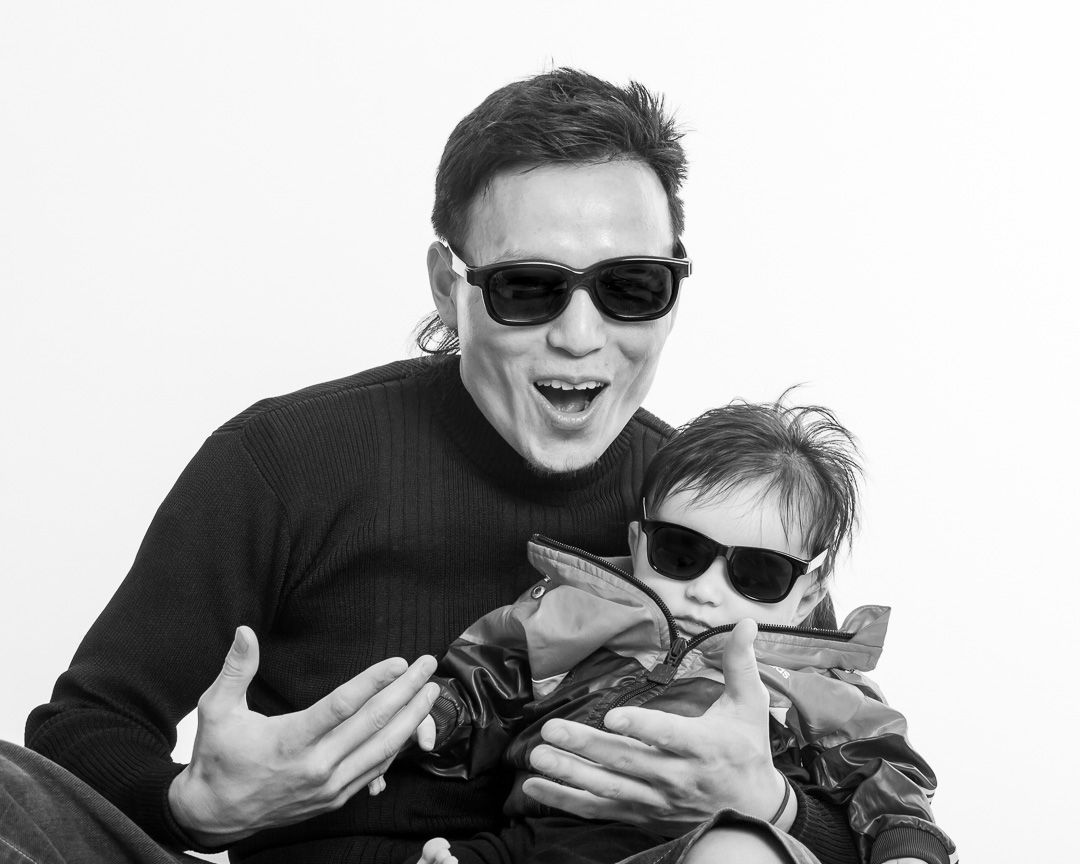 Black and white photo of people wearing sunglasses making playful expressions.