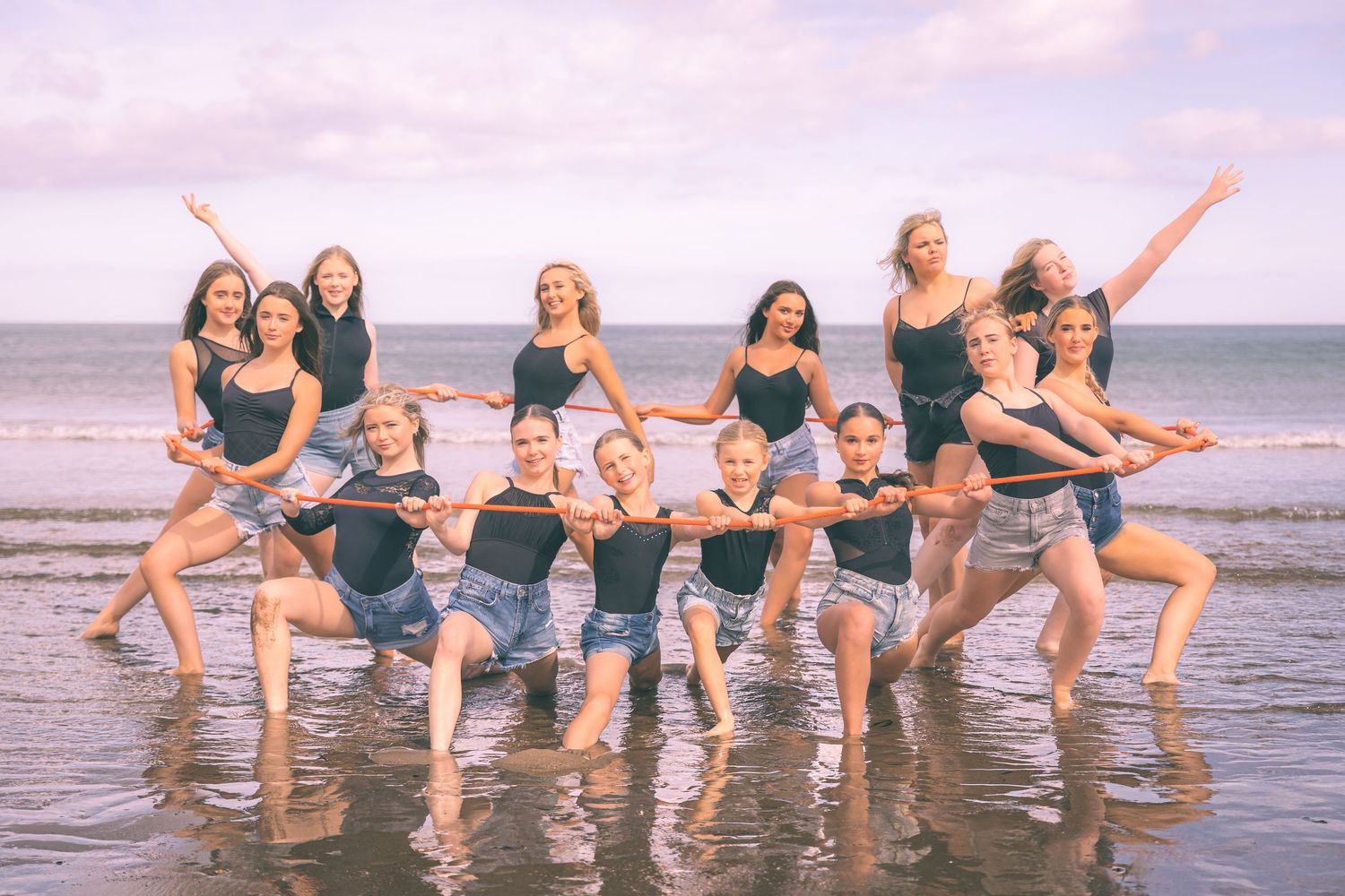 A group of friends splashing and playing in the ocean waves at sunset, creating a joyful beach scene.
