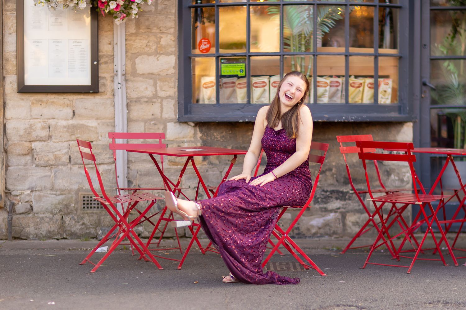 Photo shoot with red outdoor cafe furniture and stone building backdrop.