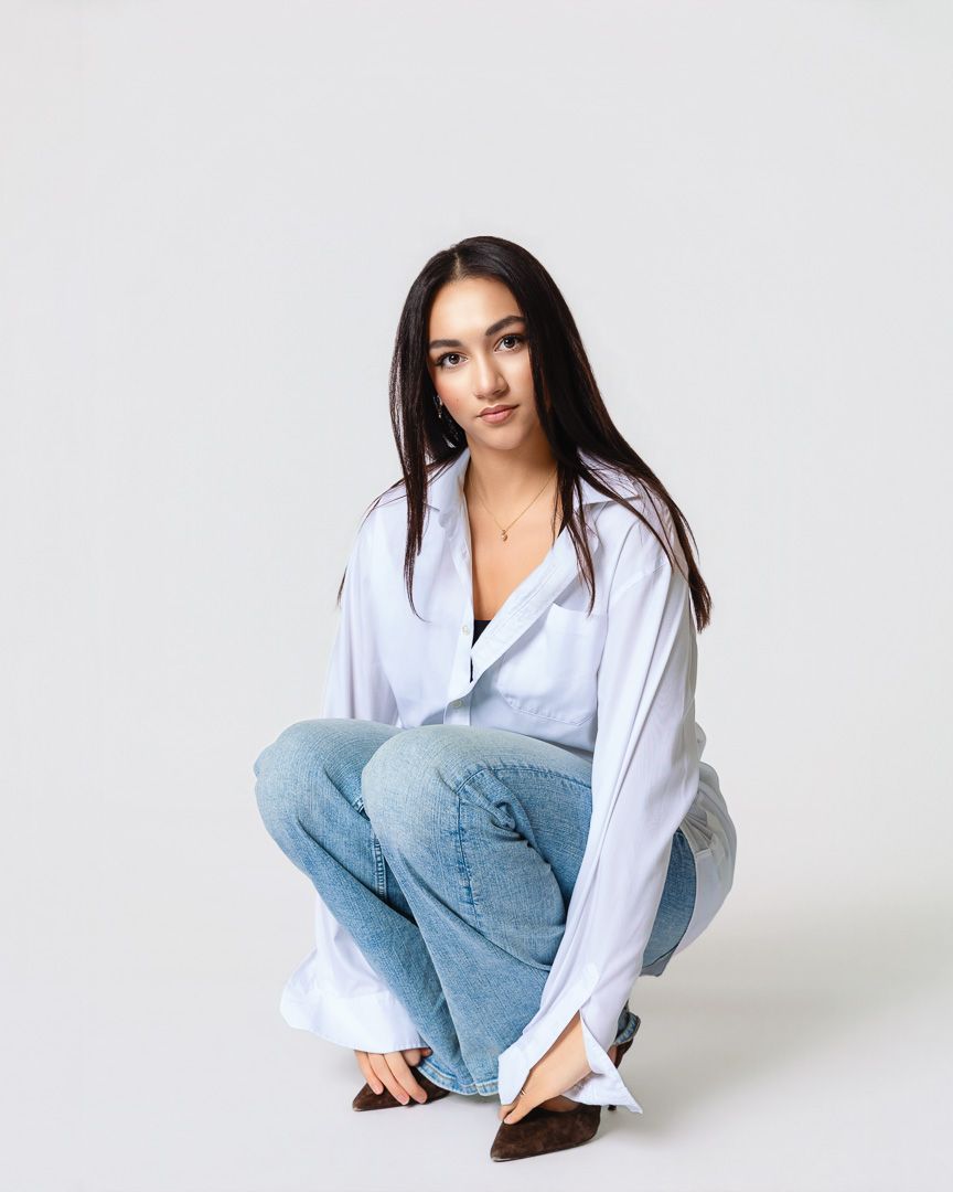 Model wearing white button-down shirt and light blue jeans poses in casual studio portraits against white background.