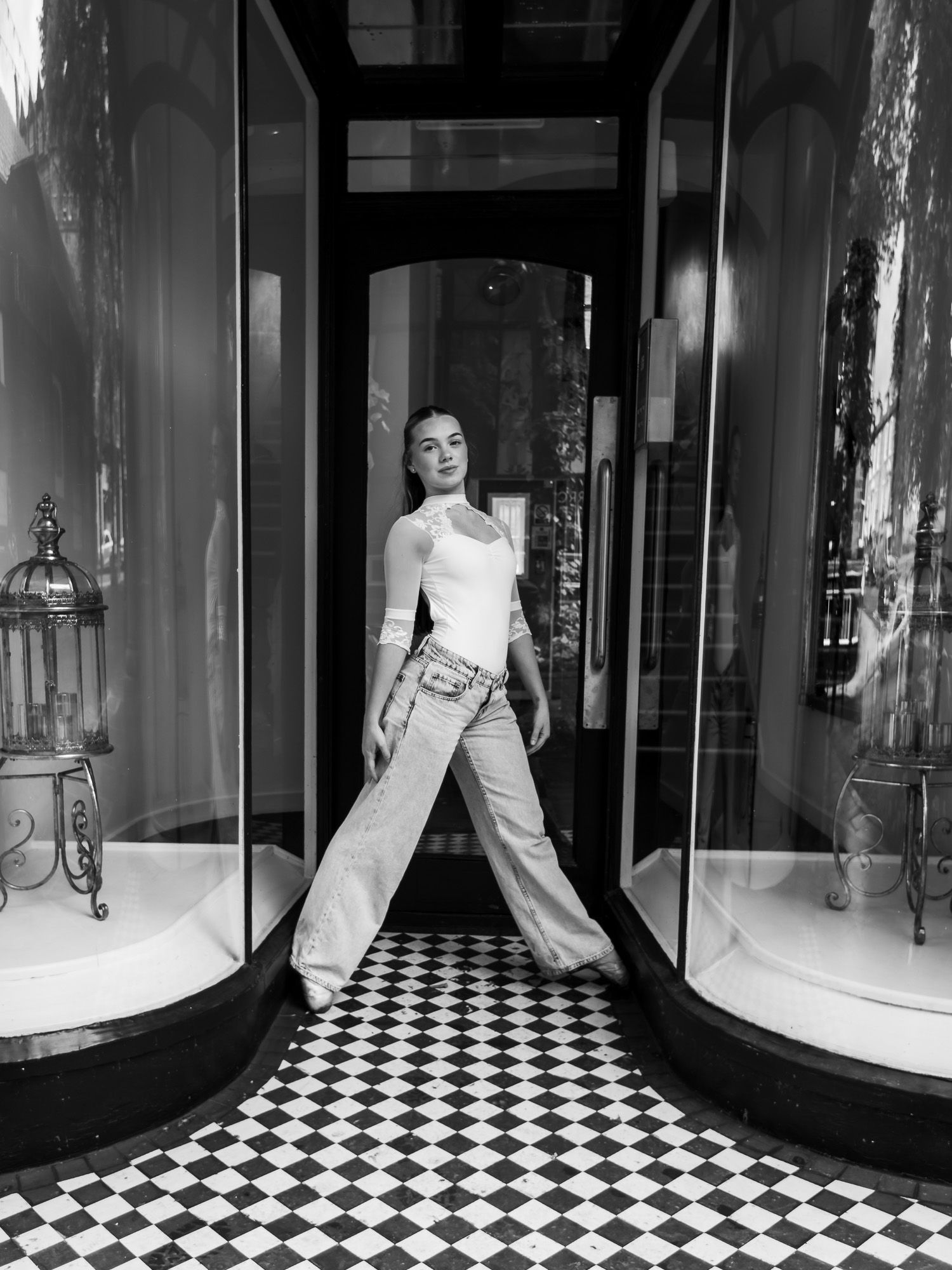 A black and white photograph showing a storefront entrance with curved display windows and checkerboard floor tiles.