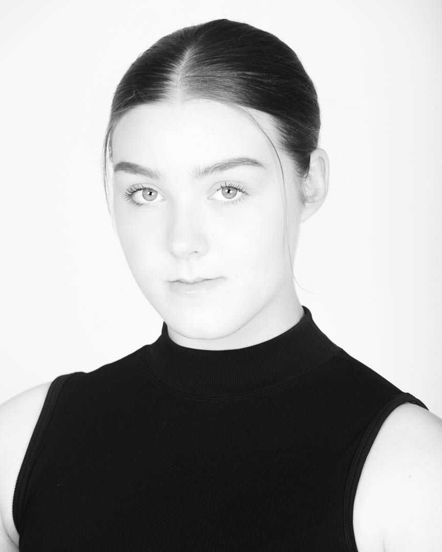 Black and white headshot of a young woman with hair pulled back, wearing a sleeveless black turtleneck top.