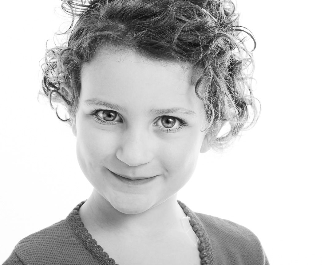 Series of black and white headshots featuring someone with curly hair making gentle smiles.