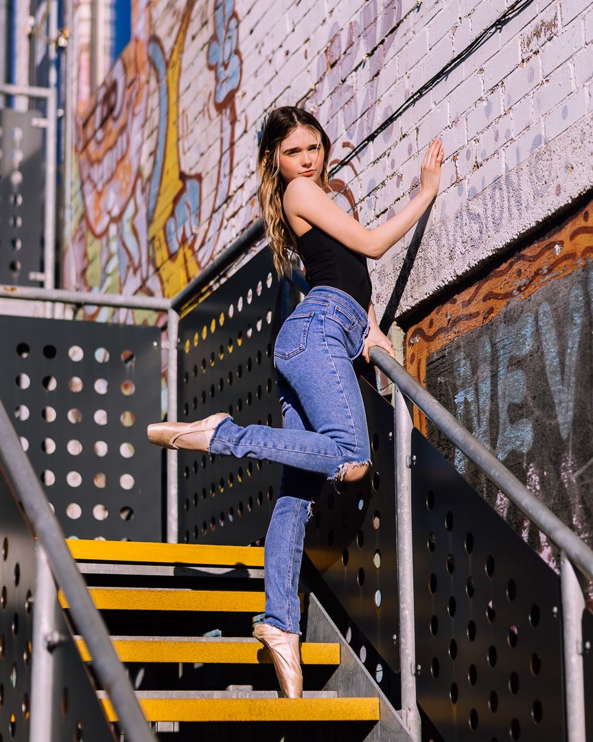Dancer in casual wear practices moves on industrial metal stairs.