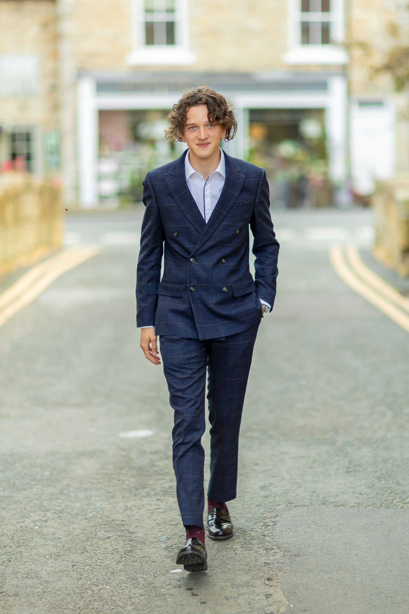 Person in navy suit walks confidently down a stone paved street.