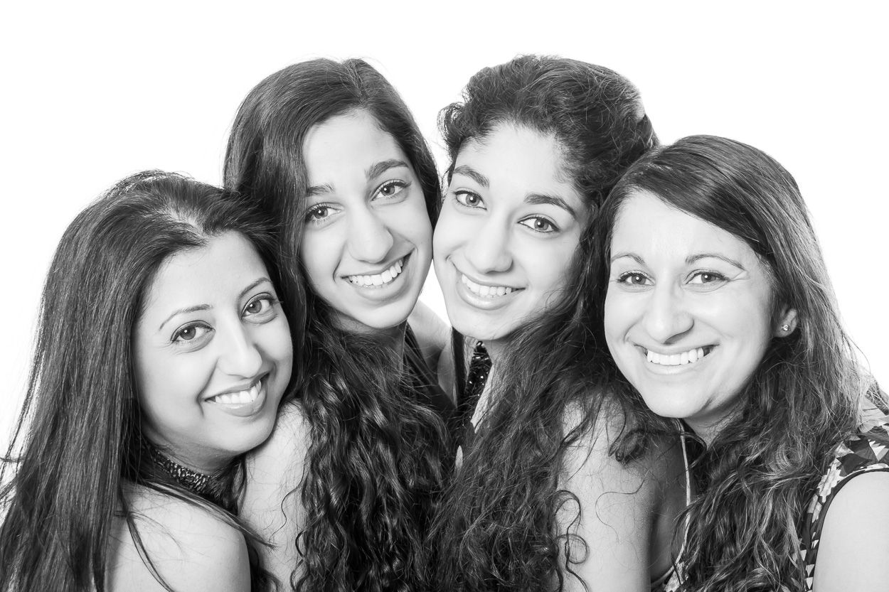 Black and white studio portrait of four friends smiling together.